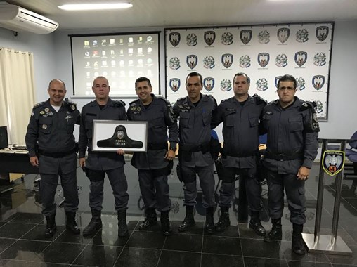 Cabo Scarpi segurando o braçal recebido pelo Major Ríodo ladeado pelos militares companheiros da Força Tática