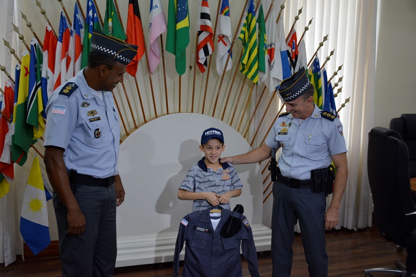 Momento em que o pequeno Gustavo recebe a farda da Polícia Militar